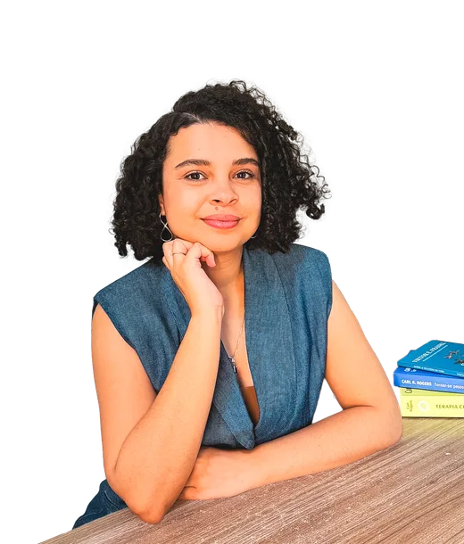 Elisa Costa sorrindo, com a mão no queixo, apoiada numa mesa com livros de Carl Rogers e Viktor Frankl